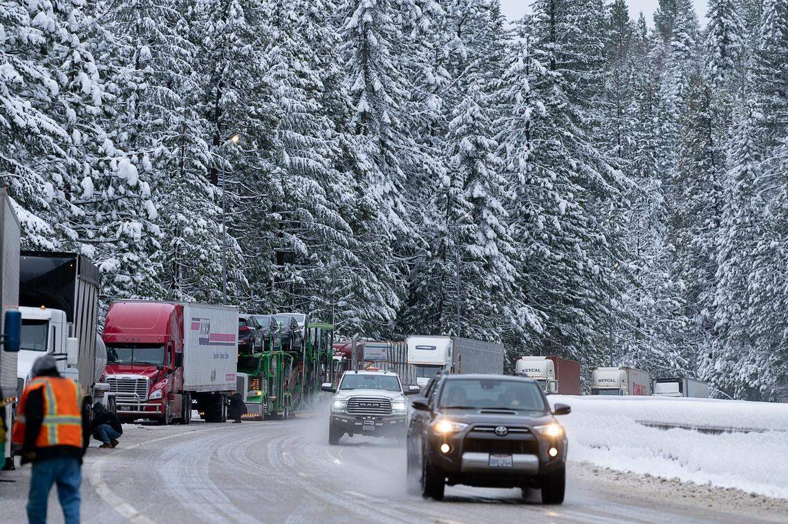 Truck drivers install chains as vehicles drive slowly up Interstate 80 east near Blue Canyon on Wednesday, Jan. 27, 2021.