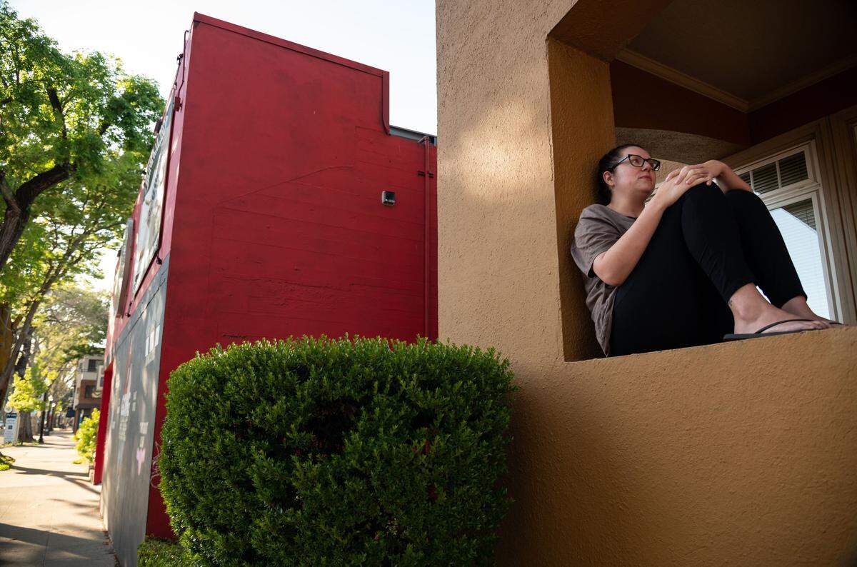 Trish Moseley, who lives on the 2200 block of J Street, sits on her porch as she spends time outside April 11 in midtown Sacramento. Moseley remarked at how strangely quiet it was for a Saturday afternoon, but added, “It makes me glad to see that people are staying in and doing what they’re supposed to.”
