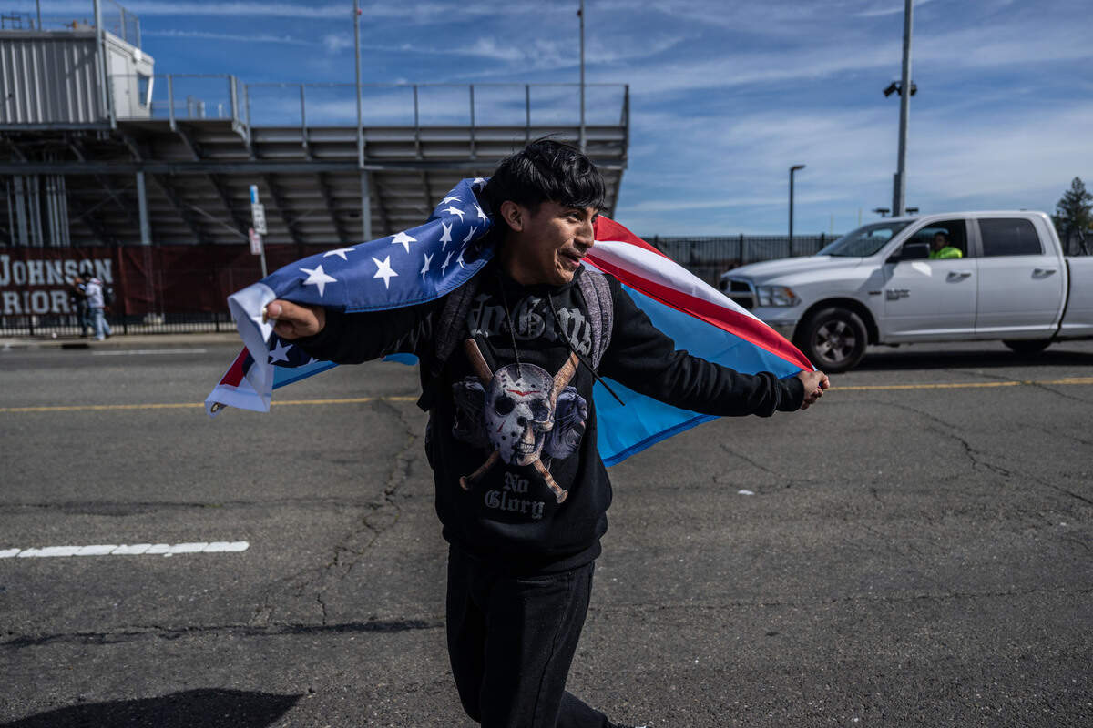 Jairo Tomas Lopez, a senior, carries an American flag with a Guatemalan flag as he and other students walk out of class Tuesday.