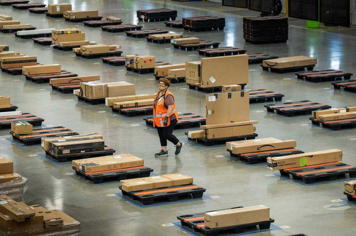 An associate at the Amazon fulfillment center in Tracy walks near between pallets on Friday. A new team of robots moves and loads packages autonomously, but much of the work is still done by workers and the company is still hiring.