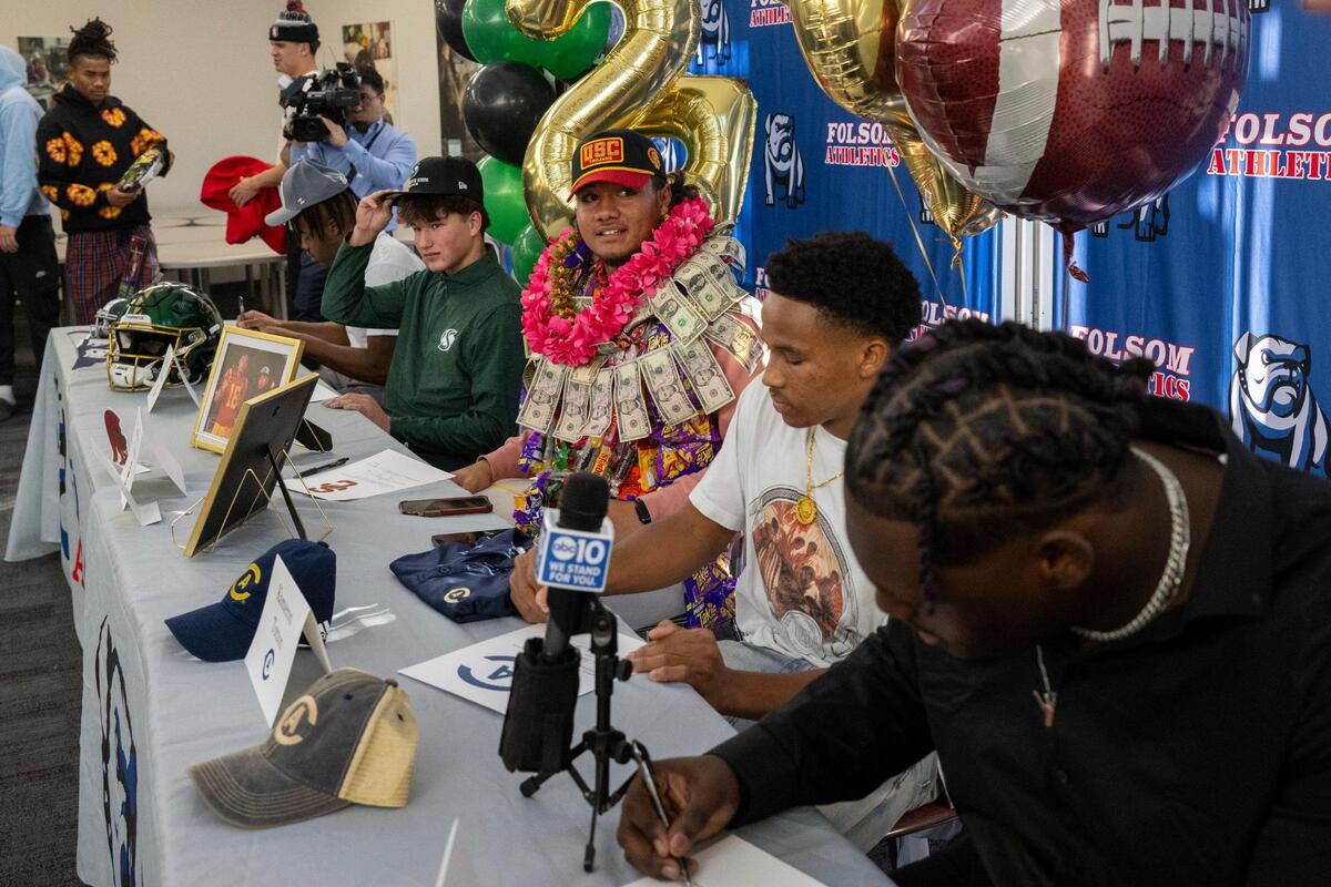 Football players Carter Jackson, Jaron Hill, Nela Tupou, Kam Totten and Josiah Sharma sign full-ride athletic scholarship commitments with Division I colleges at Folsom High School on Wednesday.
