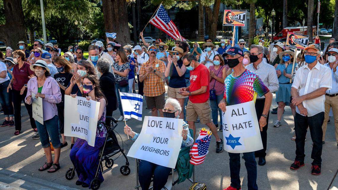 Dee Burdine, of El Dorado Hills, holds a sign and the flag of Israel, next to her husband Ted, who holds a sign that says “stop all race hate,” as they join a rally against antisemitism outside the state Capitol in Sacramento on Thursday, May 27, 2021.