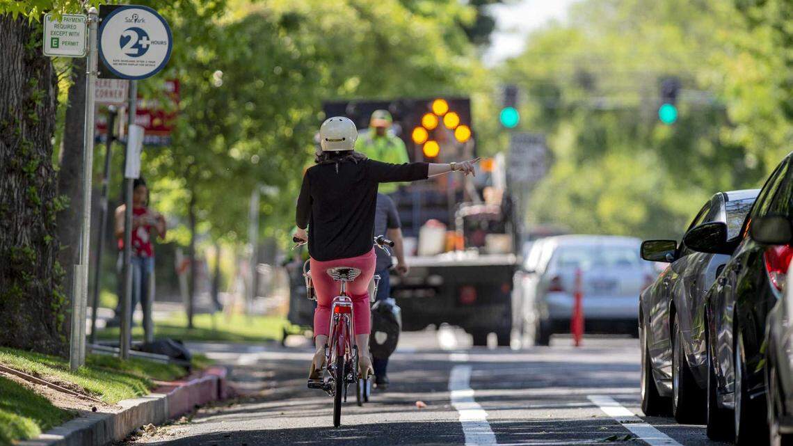 Jennifer Donlon Wyant, an active transportation program specialist with the city of Sacramento, makes a right turn signal while filming a video for the city of the new bike lanes at 13th and P Street in 2018. Jennifer Donlon Wyant, an active transportation program specialist with the city of Sacramento, signals a right turn while recording a video about new bike lanes at 13th and P streets in 2018. The city is now considering concrete-separated lanes as a new standard to improve safety and reduce maintenance costs.