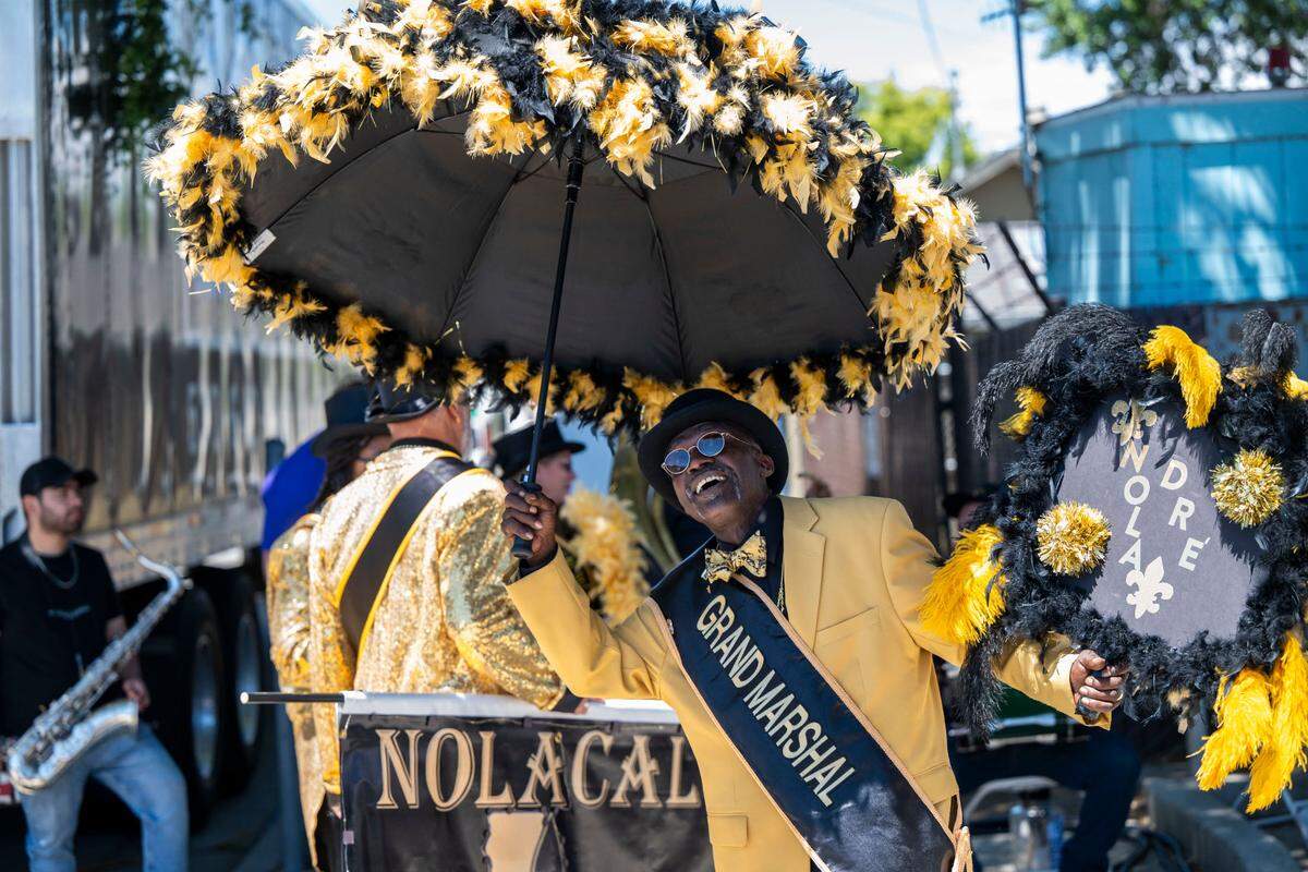 Dré Benjamin, Grand Marshall of the NolaCal Second Liners, walks around with a decorative umbrella at the City of Isleton Crawdad Festival on Sunday.