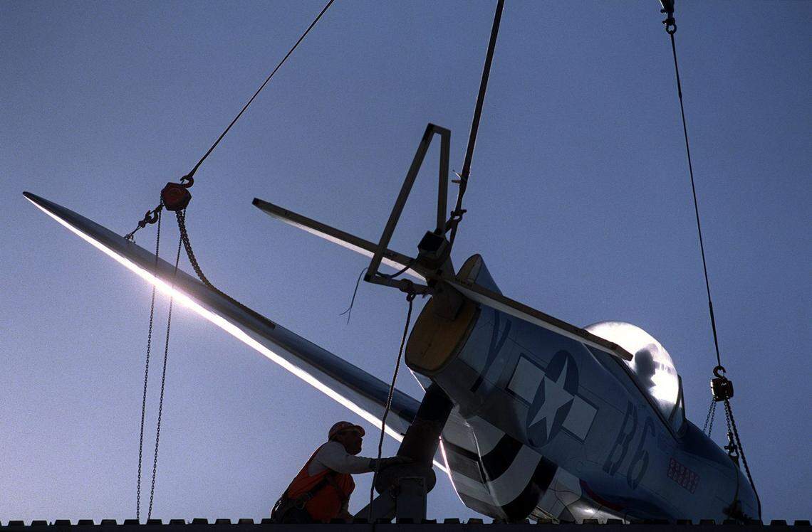 A replica of Gen. Chuck Yeager’s P-51 Mustang WWII era fighter plane is lifted on Dec. 7, 1999, by a crane atop a 46-foot reproduction of an airport control tower built outside of the new Aces Supper Club off Interstate 80.