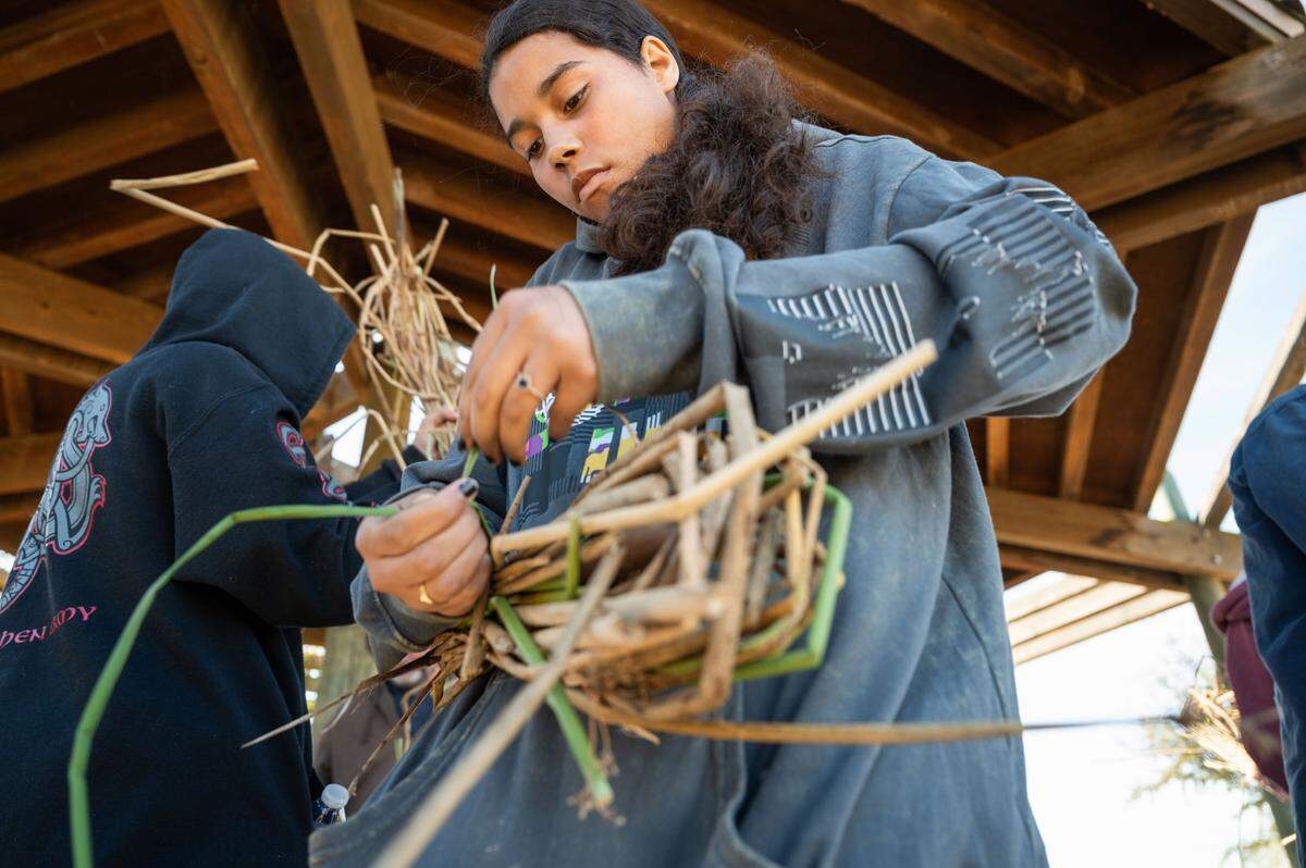 Annissa Davis, 14, from the Yocha Dehe Wintun Nation, learns how to make a bundle with reeds that were used during the Leok Po cultural burn demonstration using Indigenous knowledge and customs Friday.