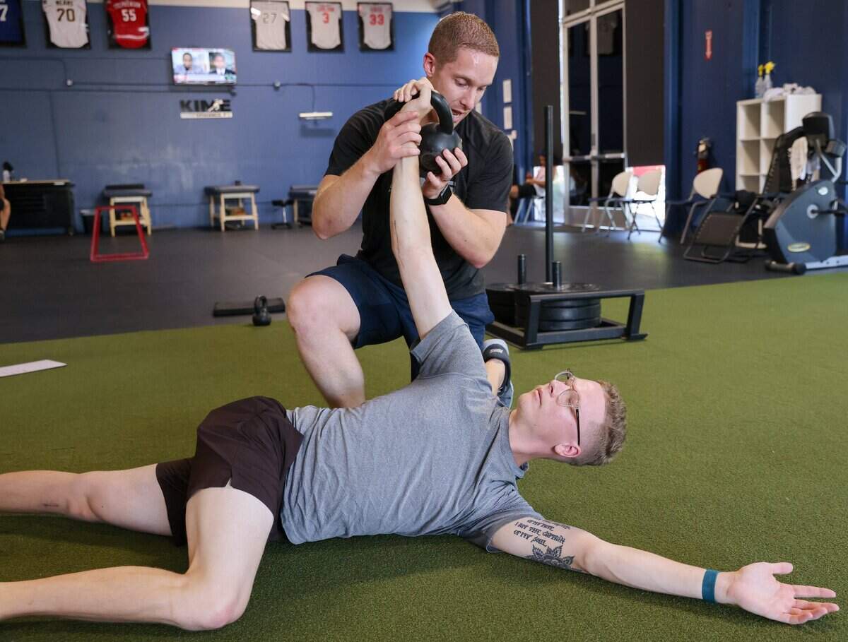 Physical therapist Evan Hauger shows a new exercise to former Sac State pitcher Stone Churby at Kime Performance Physical Therapy in Sacramento on June 30.