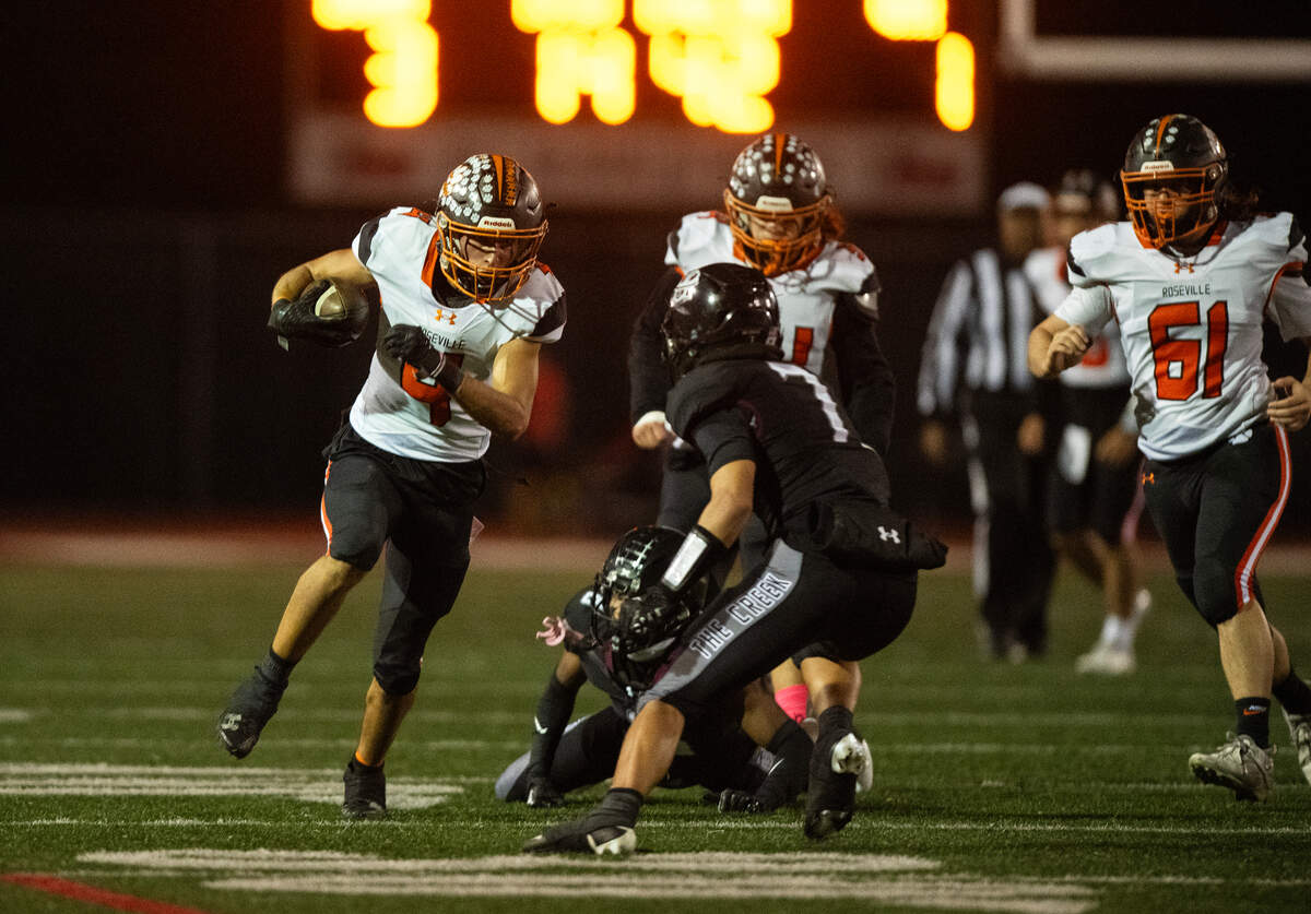 Roseville Tigers running back Aaron Salas (4) picks up a first down before being tackled by Woodcreek Timberwolves defensive back Dylan Perrault (7) in the first quarter on Friday at Woodcreek High School in Roseville.