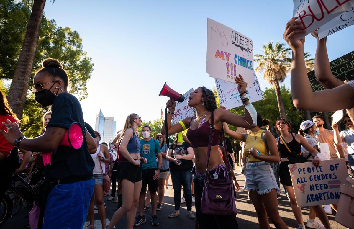 A woman who identified herself as Jada, of Sacramento, chants into a bullhorn outside the California Capitol in protest of the U.S. Supreme Court’s decision to effectively end Roe v. Wade on Friday, June 24, 2022. Lauren Babb, far left, vice president of public affairs with event organizer Planned Parenthood Mar Monte, had spoken briefly before opening the space up for others to speak. “It’s a sad day,” Babb said earlier, “people should be able to have a space to have community and feel sad until we spring into action, because it’s going to be a long game.”