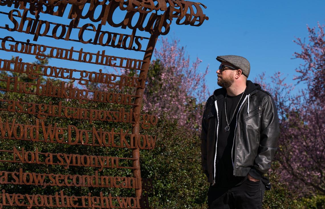 Andrew Bell, known as the the Sacramento Poet Laureate Andru Defeye, looks at a poem by Viola Weinberg, one of Sacramento’s first Poet Laureate, amid regional artist Troy Corliss’ “Poet’s Path, Circle of Laureates” art installation Wednesday, March 15, 2023, at South Natomas Community Park.