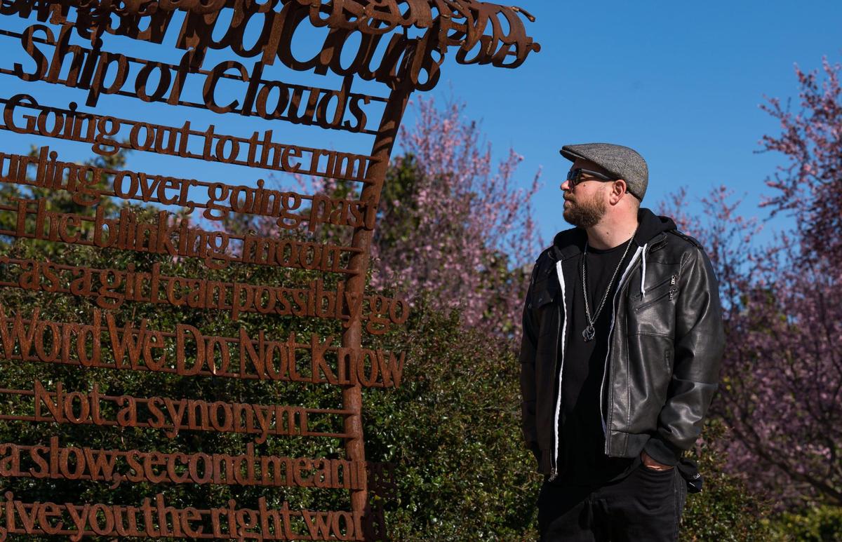 Andrew Bell, known as the the Sacramento Poet Laureate Andru Defeye, looks at a poem by Viola Weinberg, one of Sacramento’s first Poet Laureate, amid regional artist Troy Corliss’ “Poet’s Path, Circle of Laureates” art installation at South Natomas Community Park on March 15.