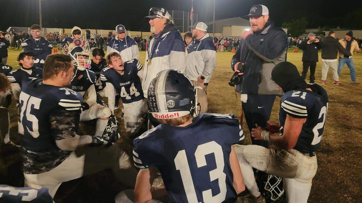 Esparto coach Ron Cristian, left, addresses the Spartans after a 2022 playoff win. This season, Esparto has battled low roster numbers and had to stop play twice in the second quarter.