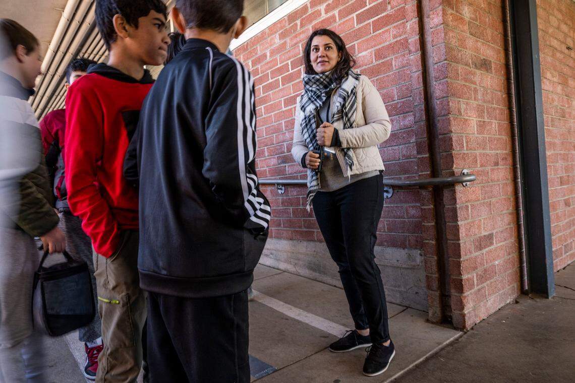 Mina Sediqi, a school community resource supervisor, at Starr King TK-8 School speaks with students between classes on Wednesday, Feb. 15, 2023. Sediqi helps newly arrived students with the transition to a new country and school.