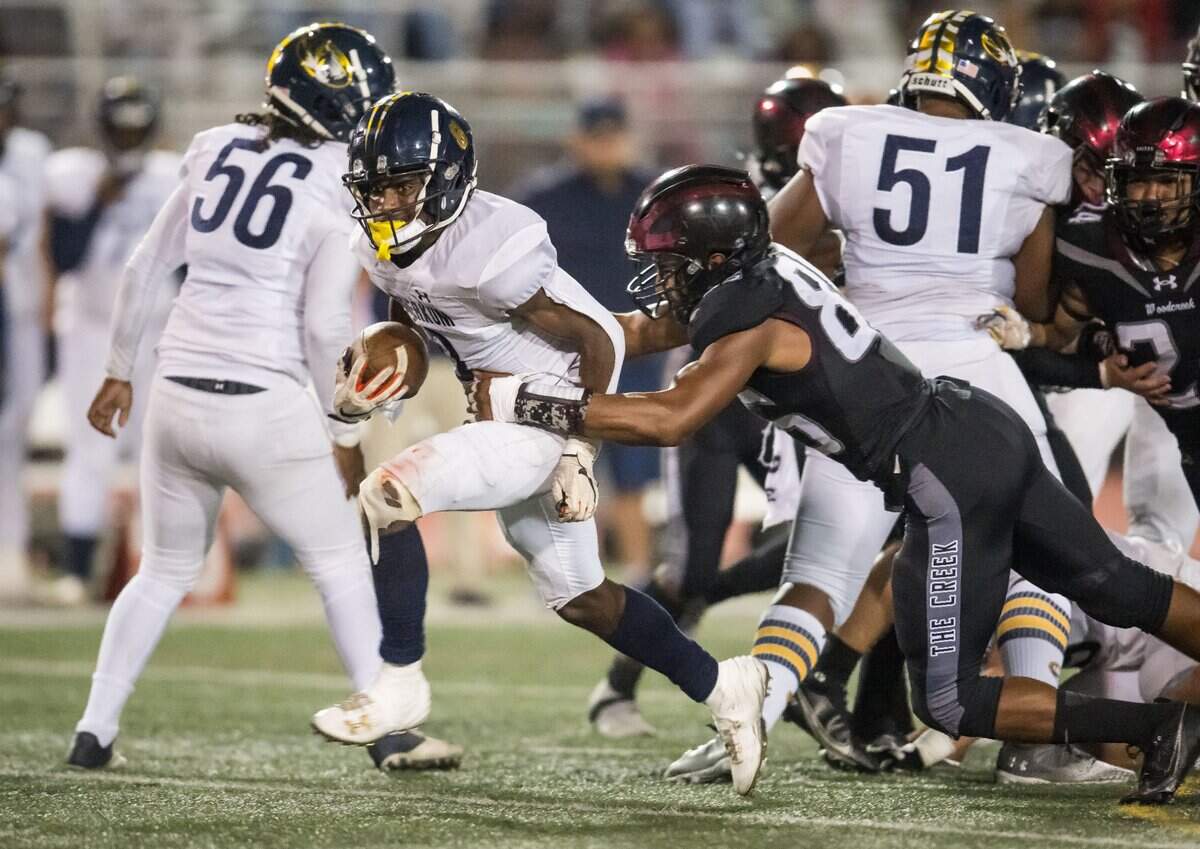 Inderkum Tigers running back Kyle Gurganious (8) runs up the middle as Woodcreek Timberwolves defensive lineman Issac Earls (85) hangs on for the tackle during on Friday in Roseville.