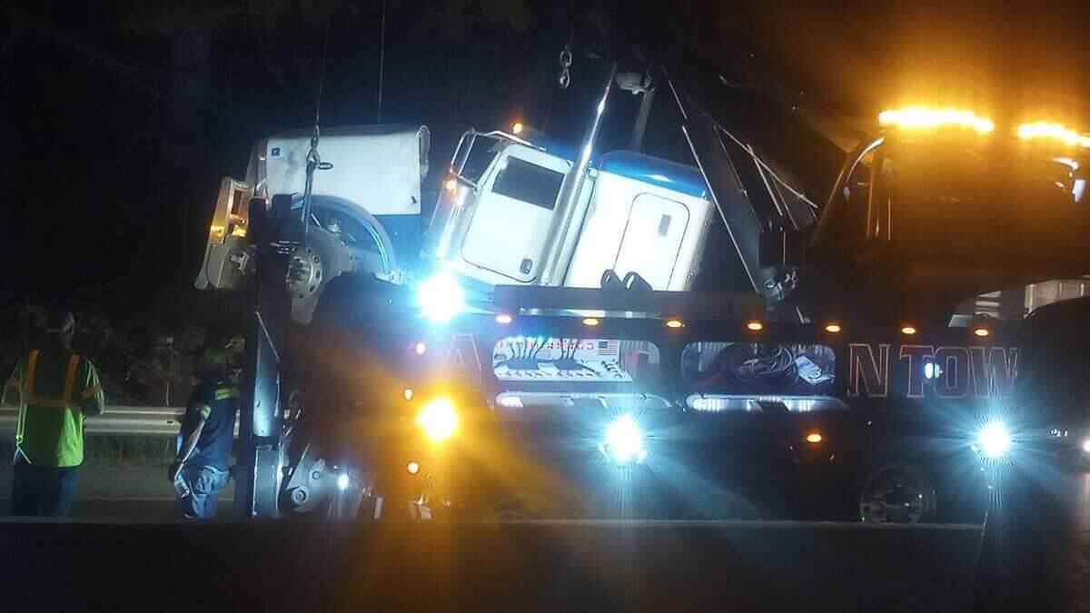 A heavy-duty tow truck works to upright a semi hauling pigs after it overturned on westbound Interstate 80 on Monday, June 22, 2026, near Colfax. The crash shut down the freeway while crews recovered escaped livestock and cleared the scene.