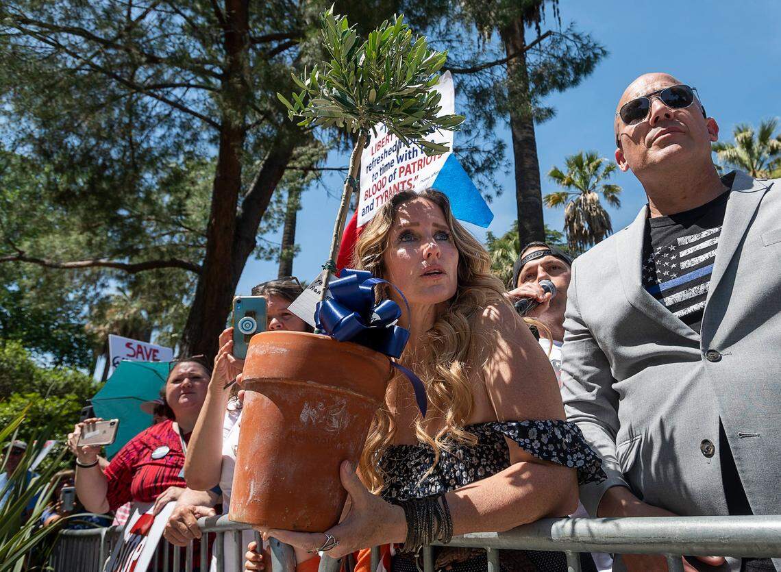 Tara Thornton of the Freedom Angels holds an olive tree intended for the California Highway Patrol officers guarding the Capitol during a protest in Sacramento against the state’s coronavirus stay-at-home orders in May 2020.