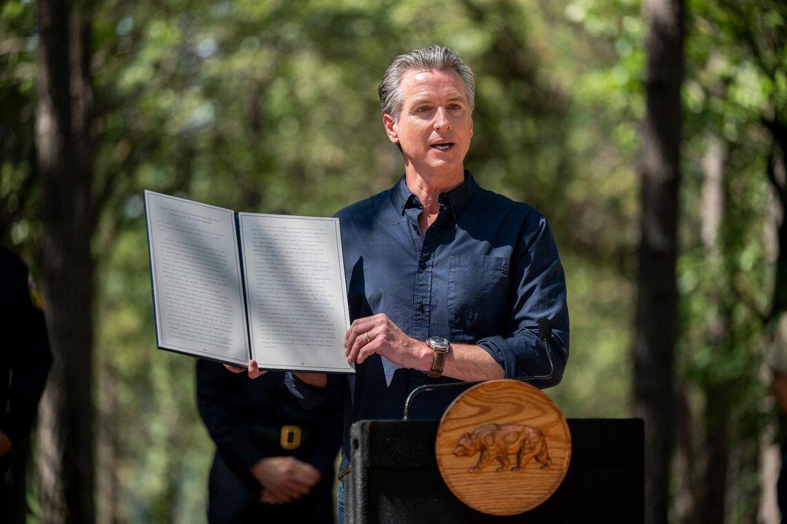 Gov. Gavin Newsom holds a copy of the executive order, which he sent to President Donald Trump, during remarks in Colfax on the federal government’s role in wildfire prevention on Tuesday.