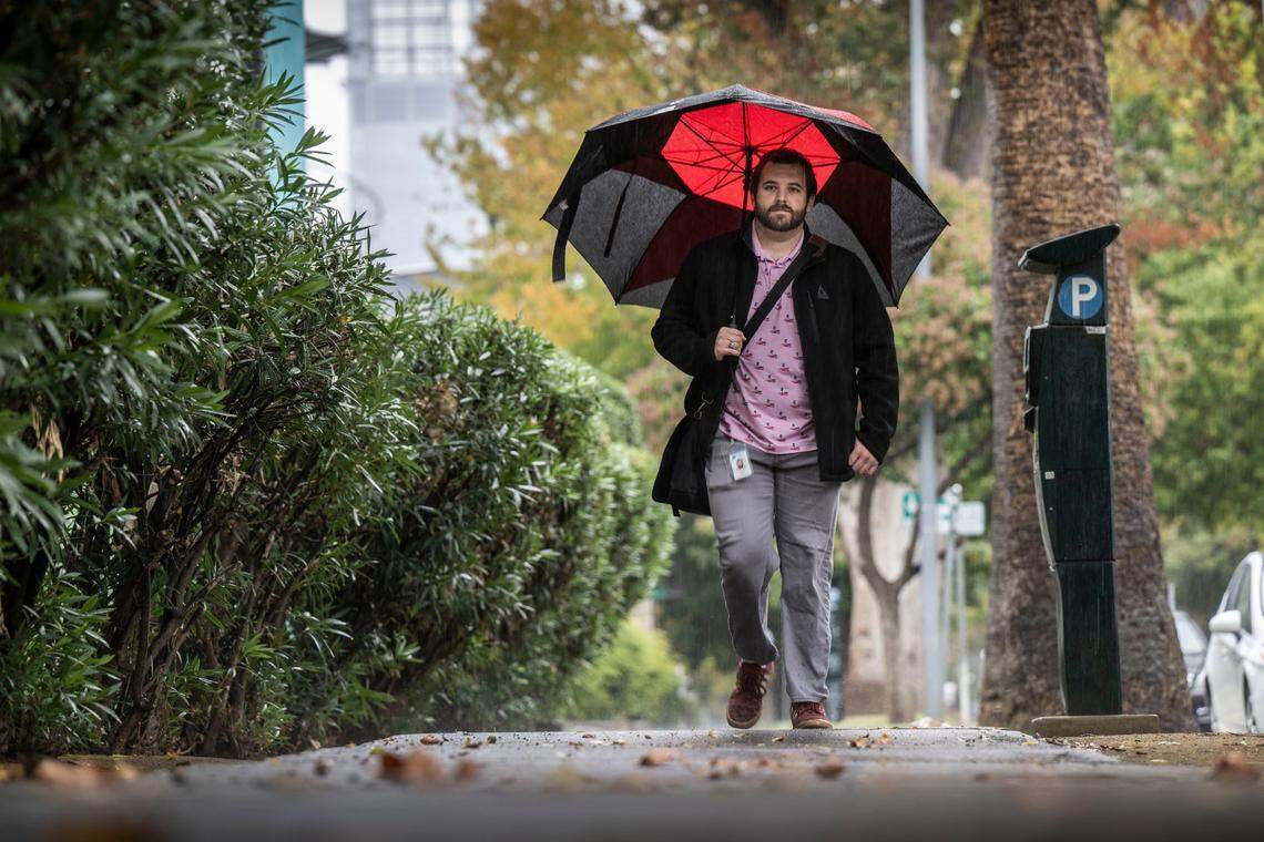 State parks worker Sawyer Greisen walks to his car in the rain on 7th Street in downtown Sacramento on Tuesday, Nov. 1, 2022.