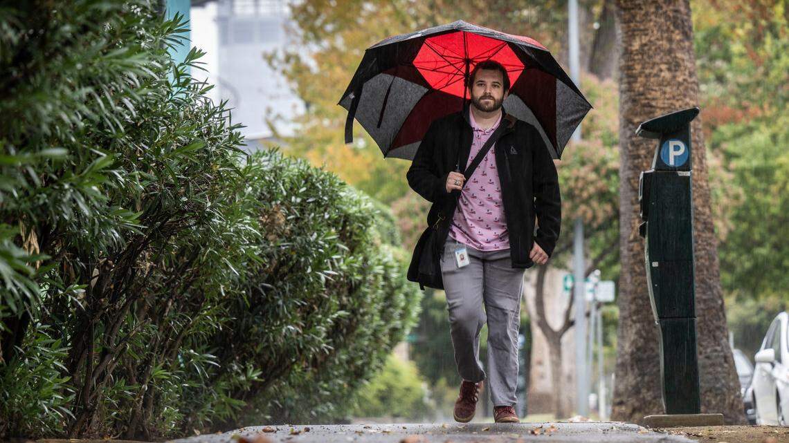 State parks worker Sawyer Greisen walks to his car in the rain on 7th Street in downtown Sacramento on Tuesday, Nov. 1, 2022.