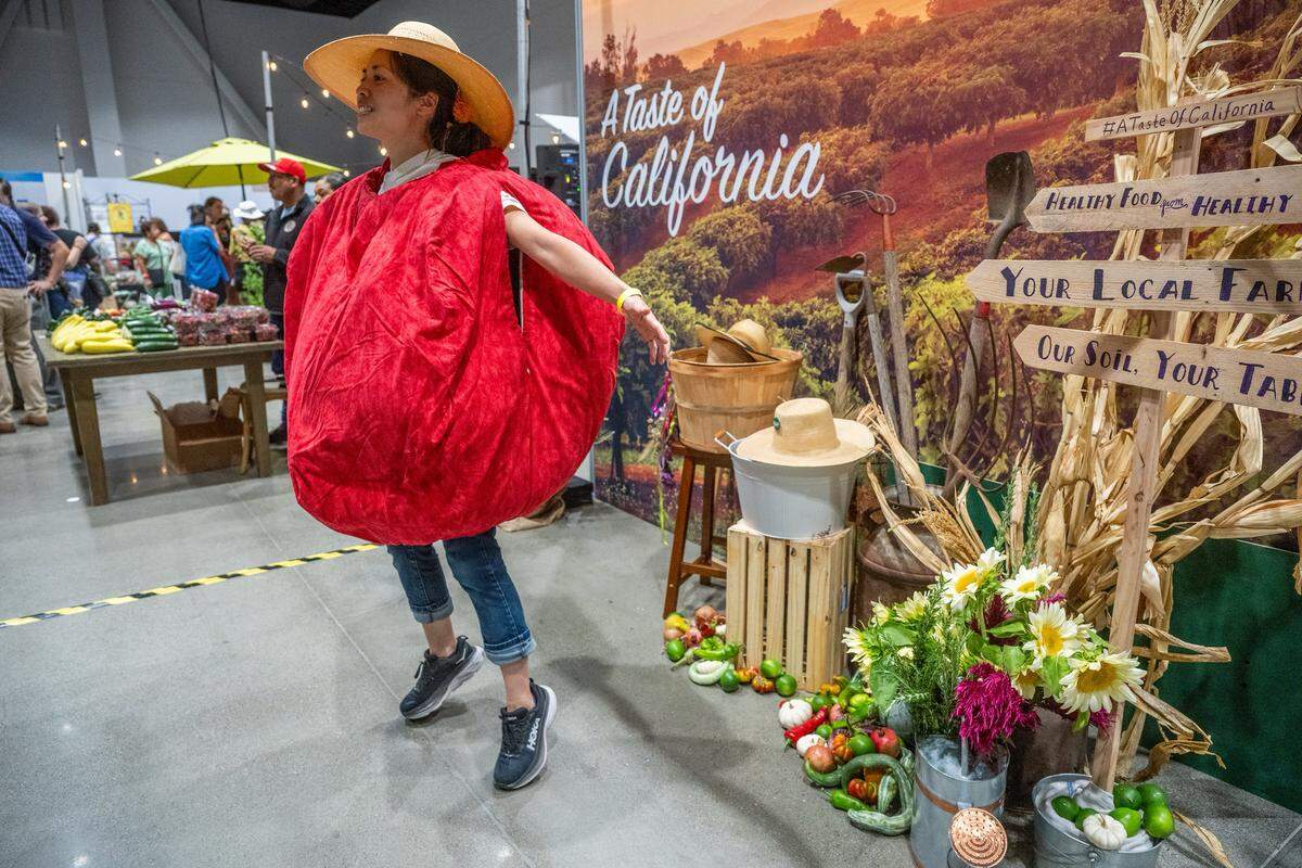 Michelle Duong jumps and chants “Sacratomato, Sacratomato!” to draw attention while wearing a tomato costume at the Terra Madre Americas festival on Sept. 26, 2025, at the SAFE Credit Union Convention Center in Sacramento. Duong, who works with the Community Alliance with Family Farmers, said her goal was to“engage people in local agriculture, think about what grows in our region — and celebrate it.” 