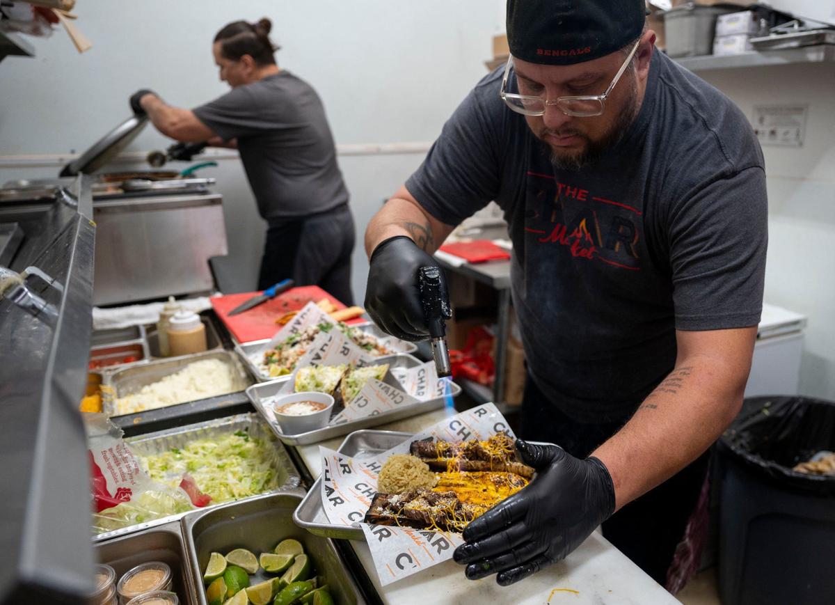 Char Market chef and co-owner Shane Cichy, right, uses a torch to melt cheese on the bone marrow Charplate in Carmichael on Thursday.