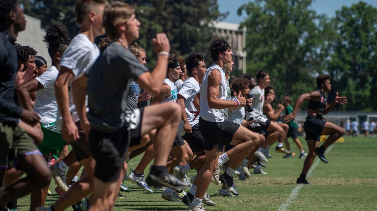 High school football players run a drill during a skills camp at Sacramento State under the eye of college coaches from across the country on Wednesday, June 15, 2022.