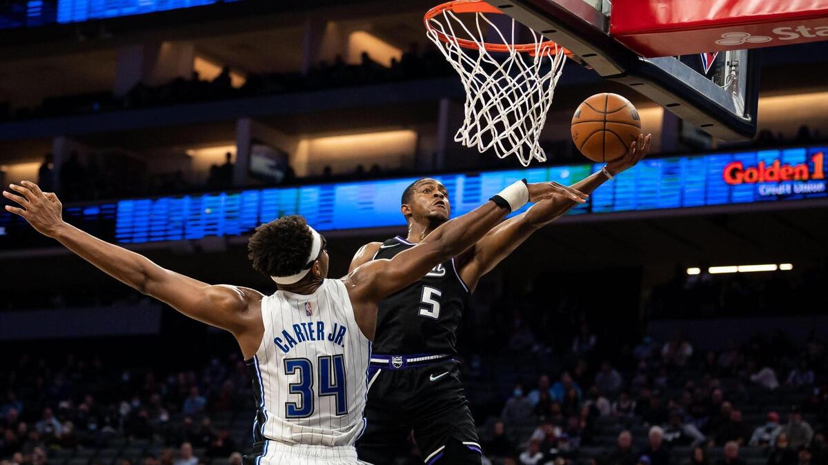Sacramento Kings guard De’Aaron Fox (5) drives and attempts a shot as Orlando Magic center Wendell Carter Jr. (34) defends during the fourth period at the NBA basketball game Wednesday, Dec. 8, 2021, at Golden 1 Center in Sacramento. The Kings beat the Magic 142-130.
