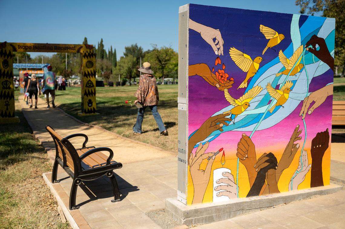 A mural showing hands of all cultures affected by the pandemic is seen where visitors can sit at the Davis Cemetery District’s COVID-19 Memorial.