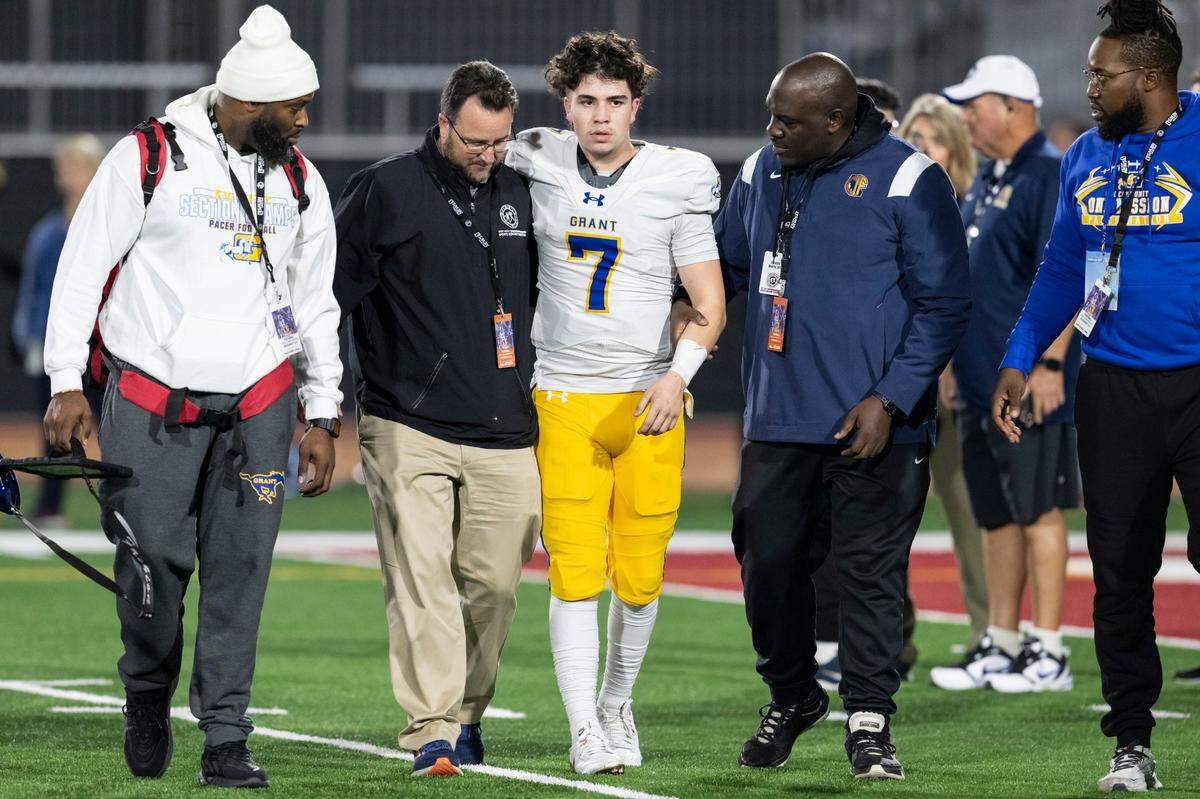 Grant Pacers quarterback Luke Alexander (7) is walked off the field after a hard hit with 15 seconds left in the first half of the 2023 CIF Division 2-AA state football championship game against the La Serna Lancers at Saddleback College in Mission Viejo.