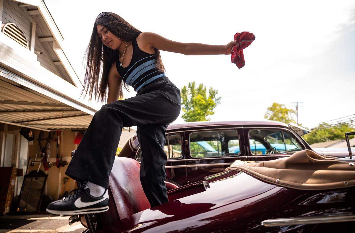 Nayeli Rodriguez, 12, carefully steps out of her father’s 1937 Buick Special after cleaning it up at home in Rio Linda on July 31, 2021, before cruising to Sacramento.