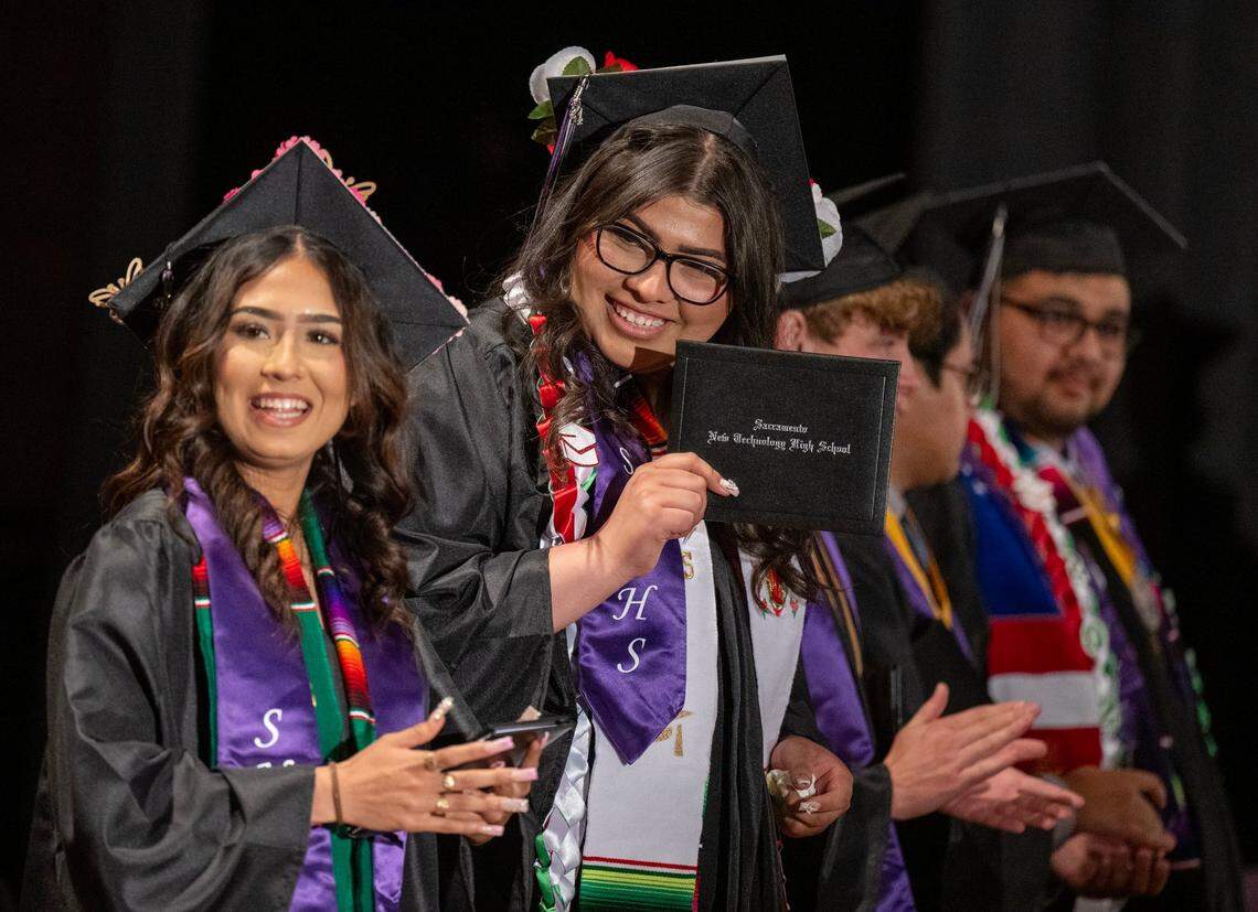 Sacramento New Technology graduate Guadalupe Villagomez, center, shows off her diploma with her friend Ana Valdivia, left, during the ceremony at Burbank High School on Friday.