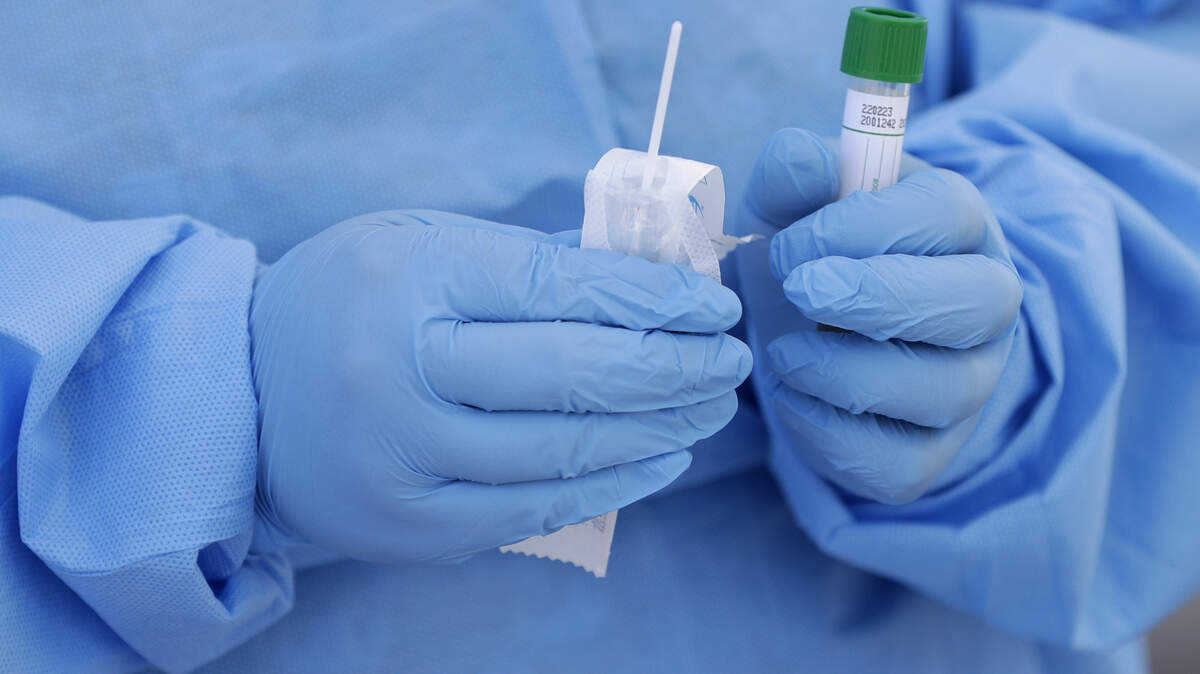 FILE - In this March 20, 2020, file photo, a health care worker prepares to collect a sample to test for COVID-19 at a drive-thru testing site in Miami. Thieves steal surgical masks. A clinic sells fake COVID-19 tests. Hate groups encourage sick members to infect law enforcement officers. Imposters pose as public health officials. As the coronavirus pandemic spreads across the globe so too do the crimes related to it. (AP Photo/Wilfredo Lee, File)
