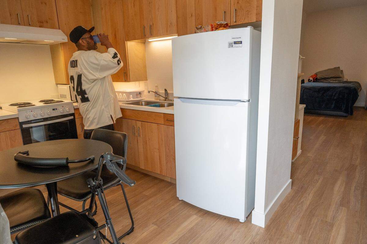 Dewayne McDaniel, 52, drinks water in his kitchen while preparing to give tours of his apartment to attendees of Northview Pointe’s grand opening on Wednesday.