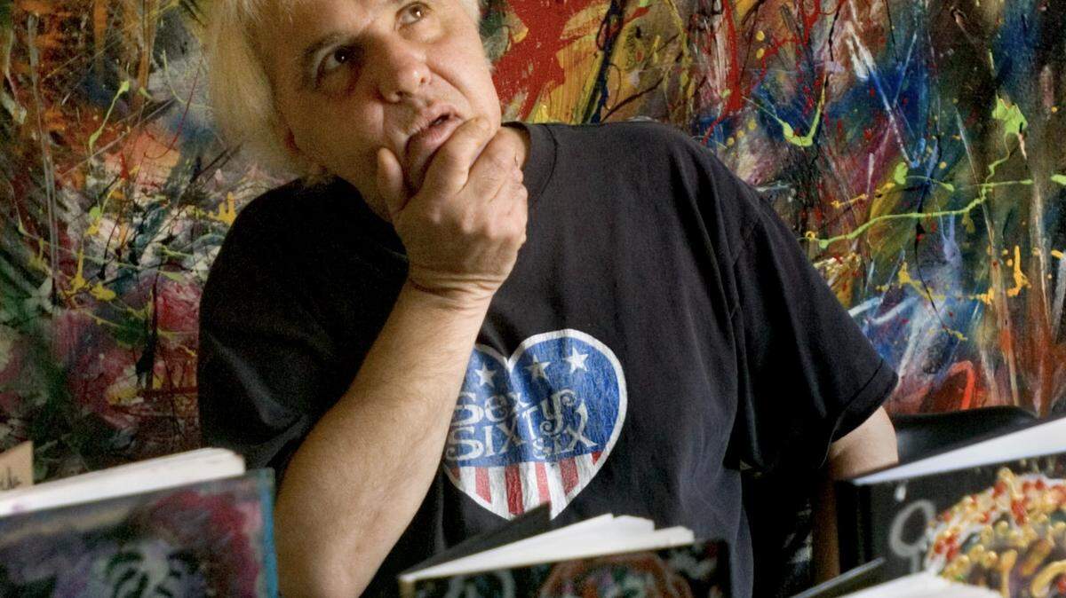 Poet B.L. Kennedy poses with poetry journals in his Sacramento apartment in 2005 in front of a huge canvas painting that he created.