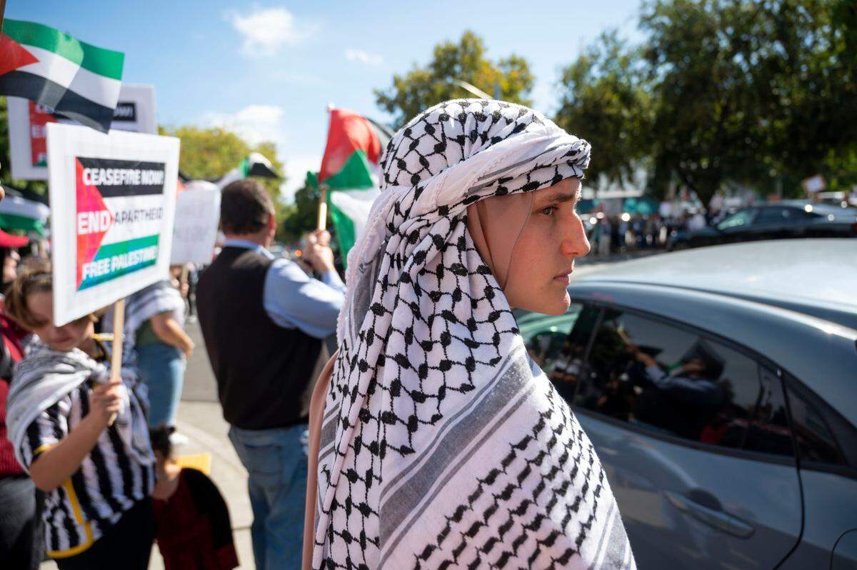 Rebekah Qinnab of Lodi keeps an eye on traffic as a large group of supporters for Palestine stand together at the corner of J and 16th streets in midtown for a rally hosted by the Sacramento Regional Coalition for Palestinian Rights on Saturday.