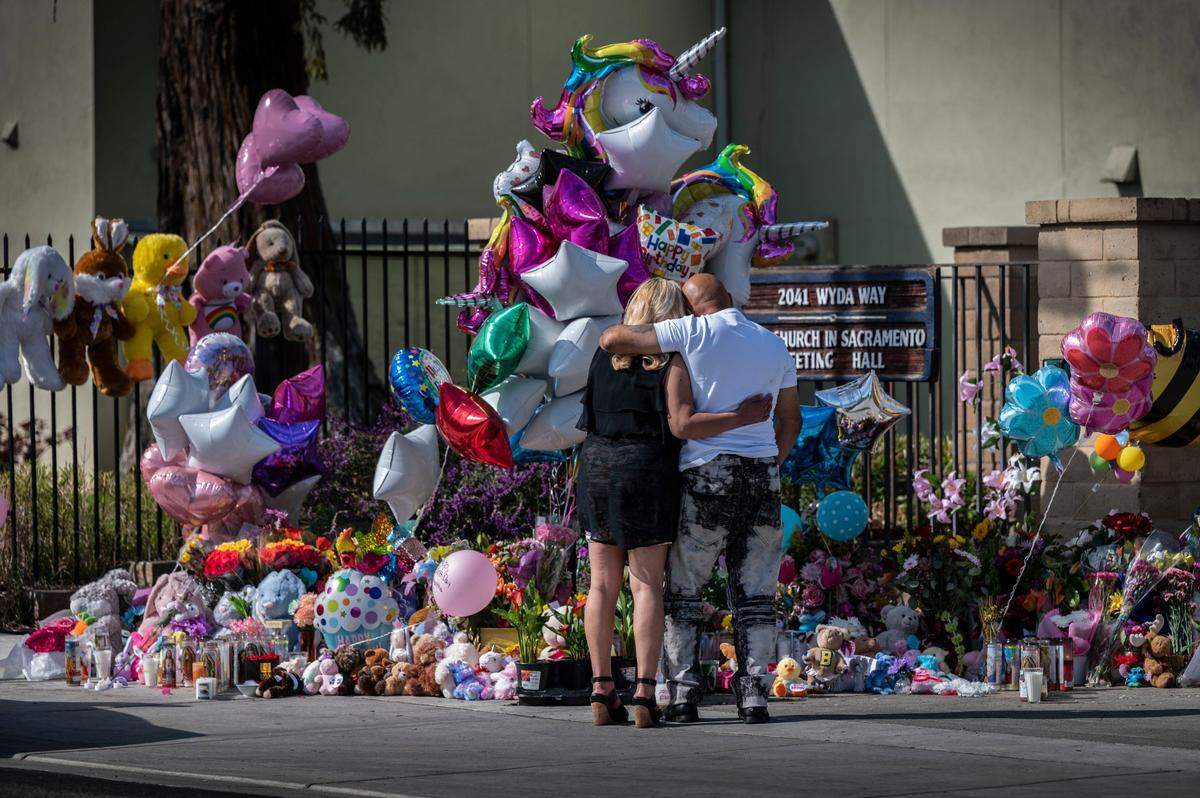 Chhavoeun Riem and her friend Deladier Monte, both of Sacramento, embrace as they take a moment to look at the growing memorial Thursday at The Church in Sacramento following a mass shooting Monday.