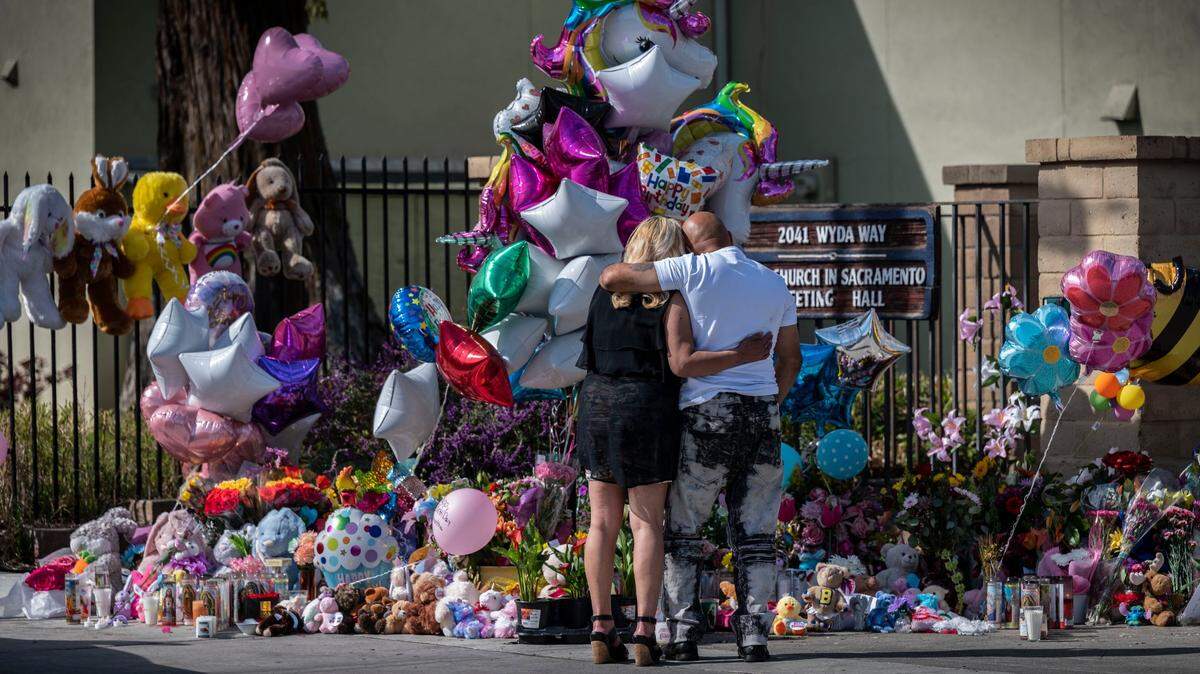 Chhavoeun Riem and her friend Deladier Monte, both of Sacramento, embrace as they take a moment to look at the growing memorial Thursday, March 3, 2022, at The Church in Sacramento following a mass shooting Monday. David Mora killed his three daughters, 9-year-old Samarah, 10-year-old Samantha and 13-year-old Samia and Nathaniel Kong, 59, a church elder who was supervising a family visit. He then took his own life.