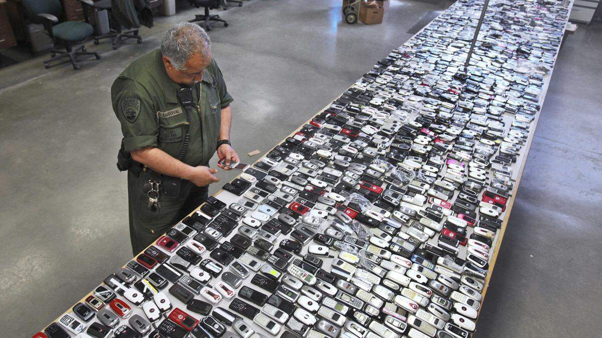 Correctional Officer Jose Sandoval inspects one of the more than 2,000 cell phones confiscated from inmates at California State Prison.