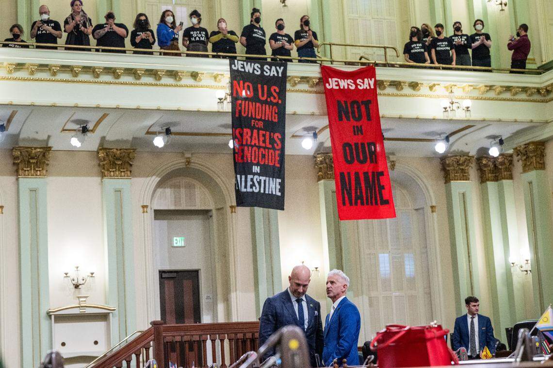 Assembly members Heath Flora, R-Ripon, and Josh Lowenthal, D-Long Beach stand on the California Assembly floor as protesters calling for a cease-fire in the Israel-Hamas war demonstrate in the gallery Wednesday. The demonstration shut down the Legislature’s first Capitol floor session of the new year.