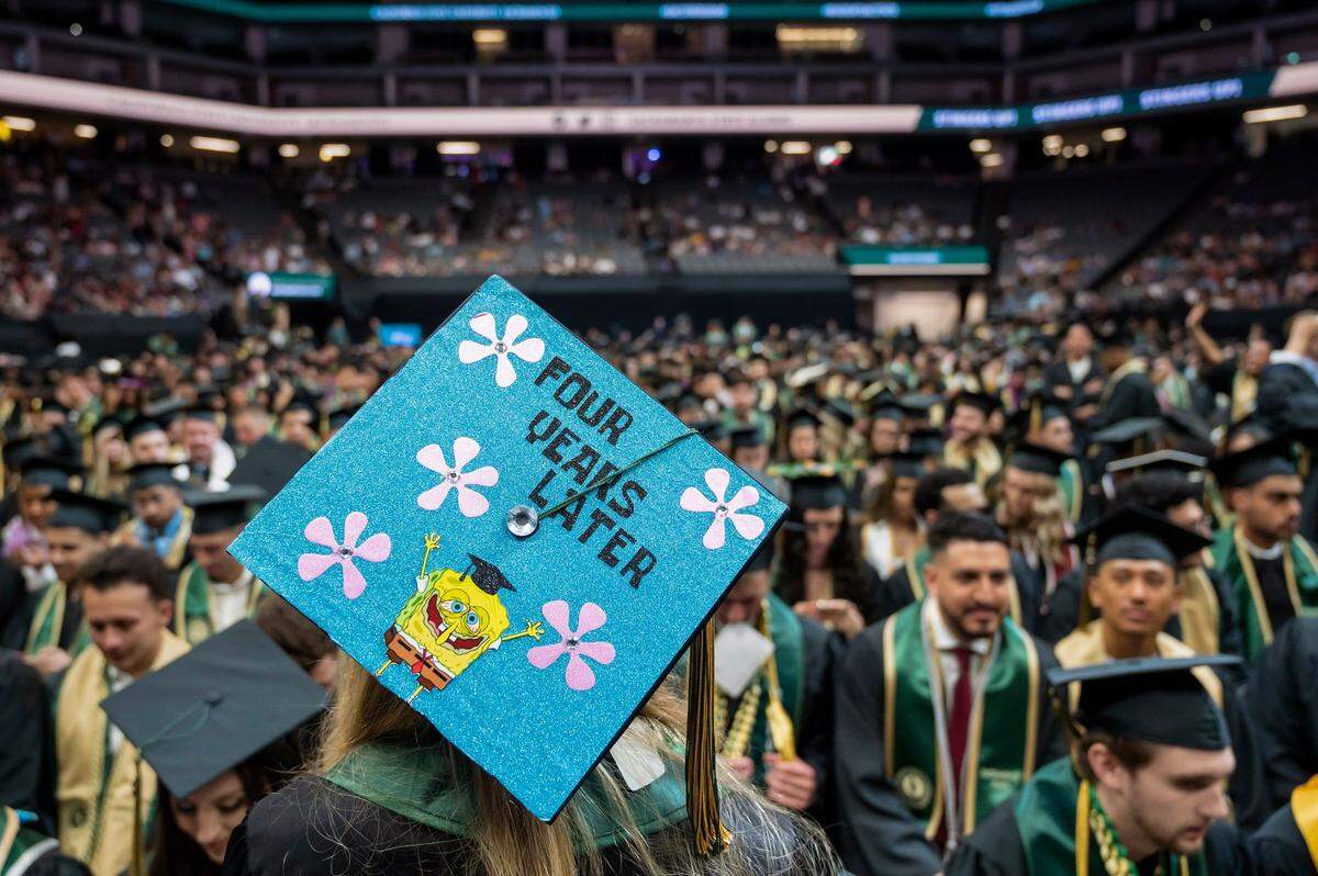 The decorated cap of Lauren Martinez reads “four years later” as she looks torward the crowd of graduates before the Sacramento State College of Business commencement on Friday.