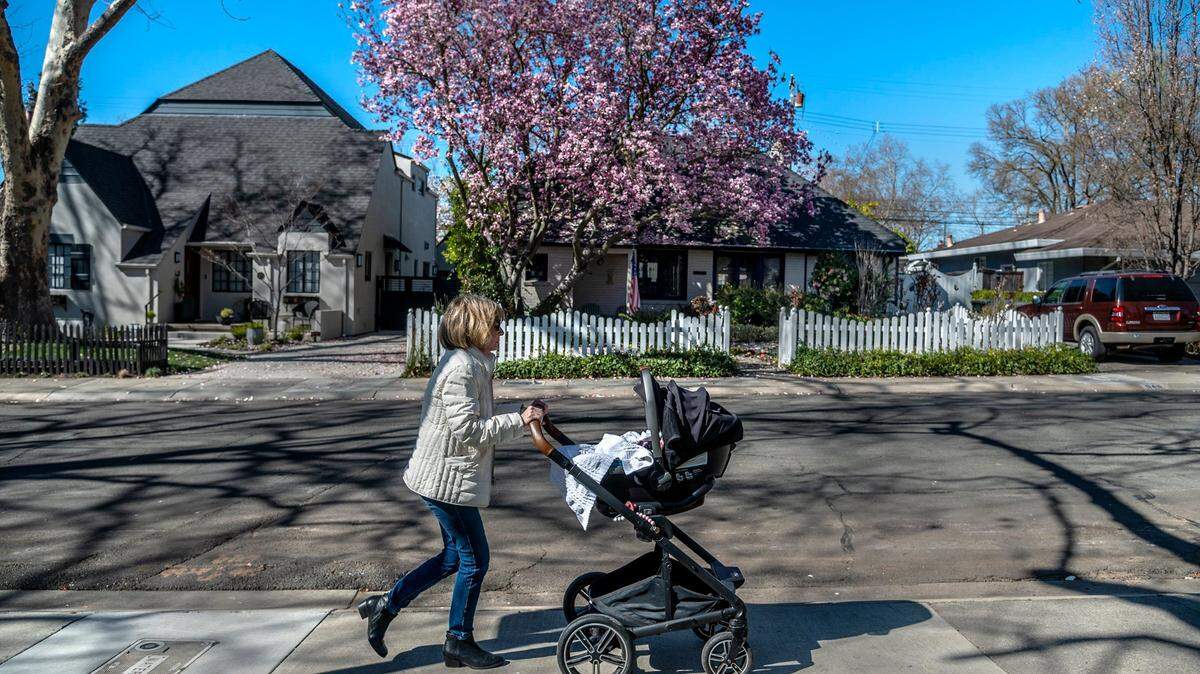 Susan Cortvriendt pushes her 9-month-old granddaughter Makena Meade in a carriage past a blooming magnolia tree on 46th Street in East Sacramento on Monday, Feb. 21, 2022. The day’s clear skies didn’t reflect an end to winter entirely. The National Weather Service issued a freeze watch that week for the Sacramento Valley.
