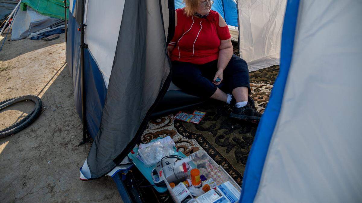 After a long walk to her tent at Morrison Creek encampment. Betty Rios, 48, sits exhausted, clutching her inhaler. She suffers from asthma and worries about how she will use her electric breathing machine now that she’s back in her tent. “My health was really better when I was in there but now its becoming really worse out here.” She was part of Project Roomkey from June to February and was asked to leave and given a 21 day voucher for a hotel that had expired.