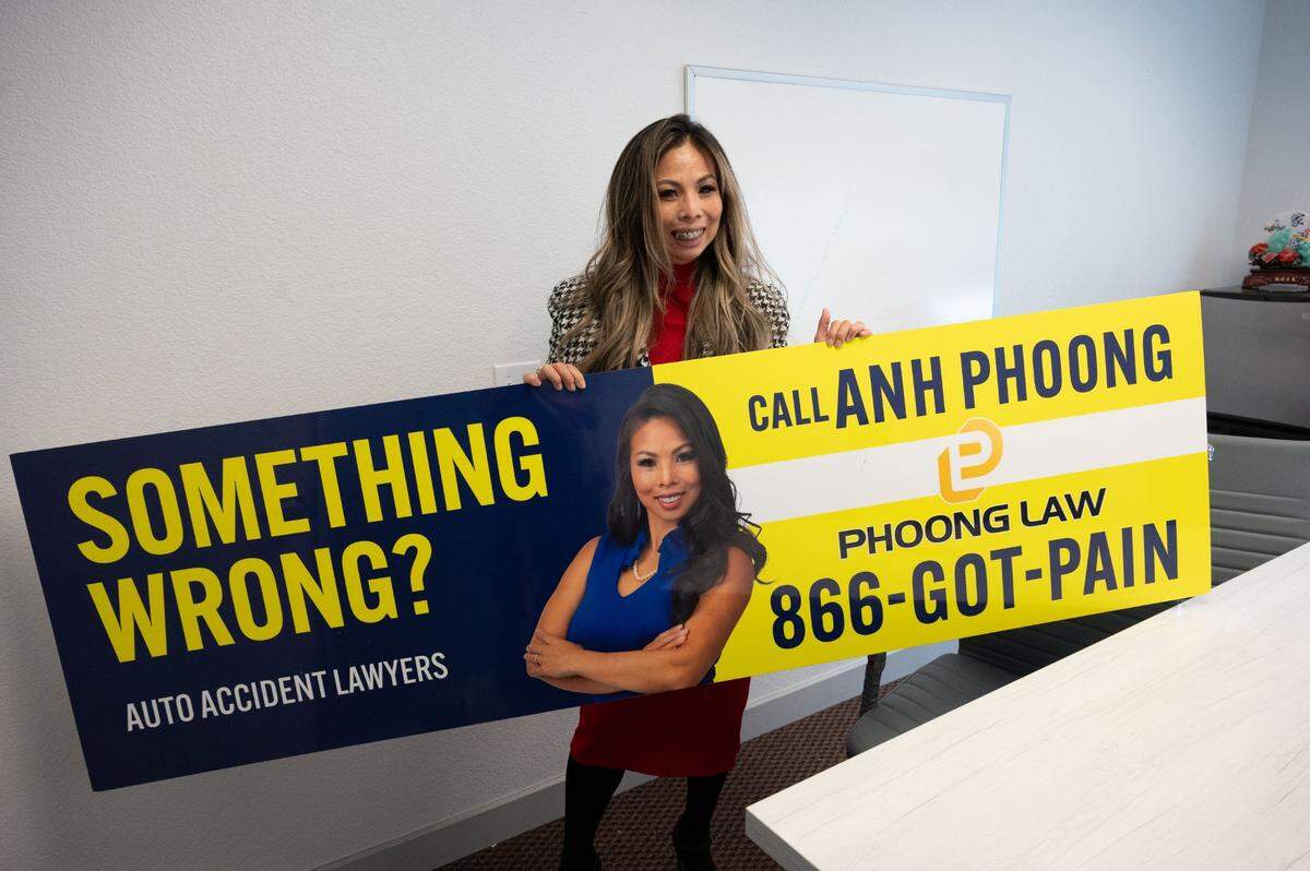 Personal injury attorney Anh Phoong holds up one of her bus billboards at her office in Sacramento on Wednesday.