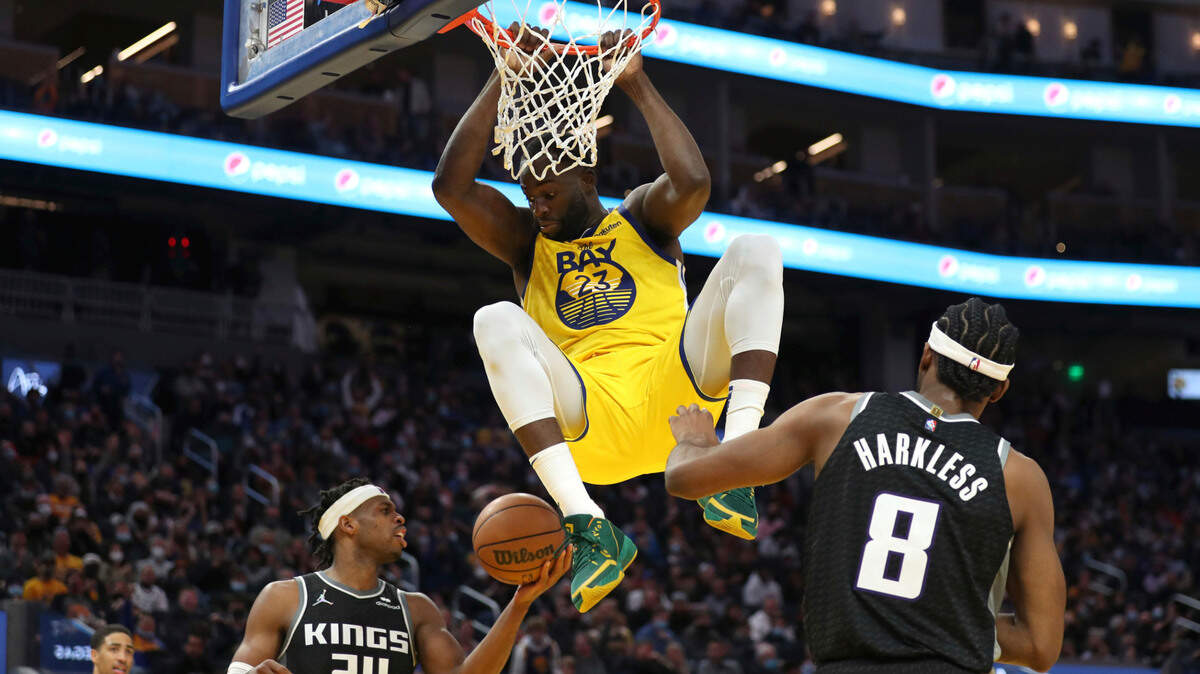 Golden State Warriors forward Draymond Green (23) scores against Sacramento Kings forward Maurice Harkless (8) and Buddy Hield (24) during the second half of an NBA basketball game in San Francisco, Monday, Dec. 20, 2021. (AP Photo/Jed Jacobsohn)