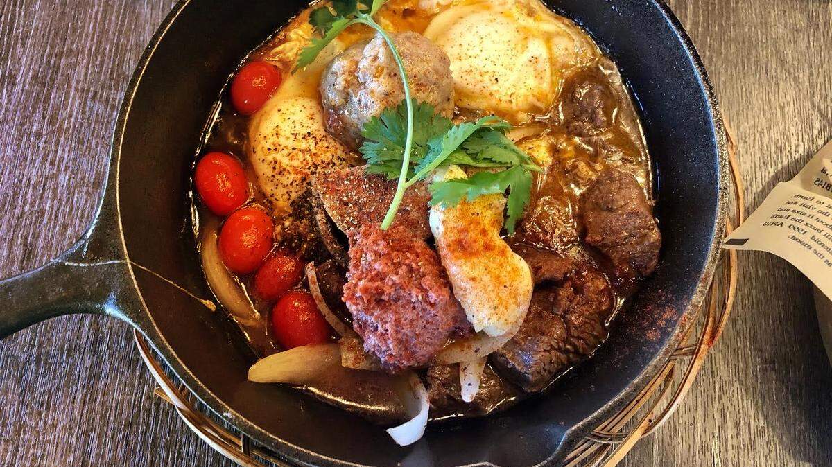 The bánh mì chảo at Saigon Oi is spiced red pâté, filet mignon chunks, poached eggs, a meatball and grape tomatoes swimming in a skillet amid a super-savory sauce, with an airy baguette on the side to dip scoop up excess juice.