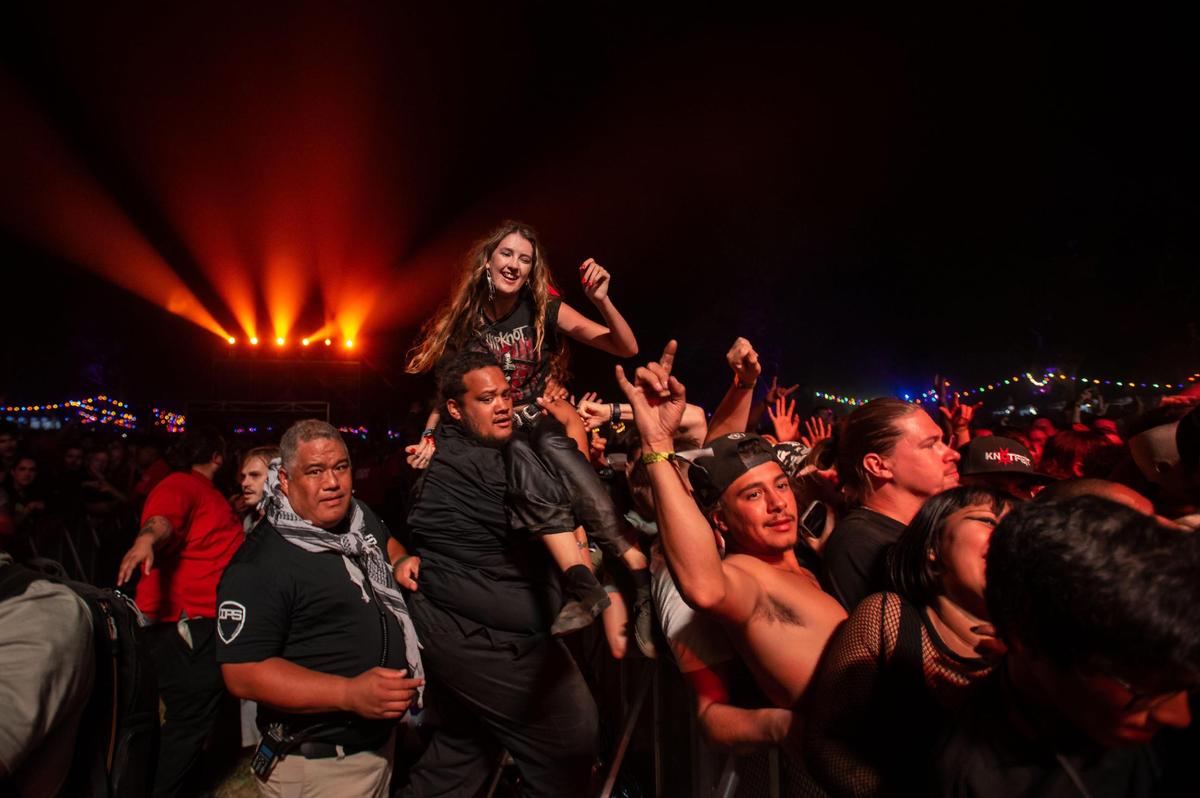 Security personnel deal with fans who crowd surf as members of Slipknot play the Jack Daniel’s Stage on opening night of the Aftershock rock festival Thursday.