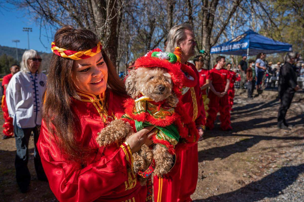 Tai Simo Molina, with Eastern Ways Marshal Arts Lion and Dragon Dance group of Sacramento, holds her dog Peaches as they participate in the dedication of Gam Saan Trail in Lotus on Friday.