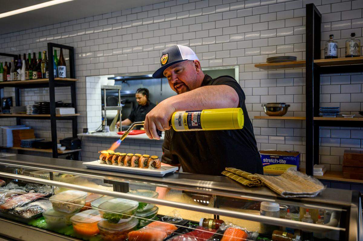 Chef Lou Valente blowtorches an uptown roll before serving it at his restaurant Southpaw Sushi in Old North Sacramento, Wednesday, August 21, 2019.