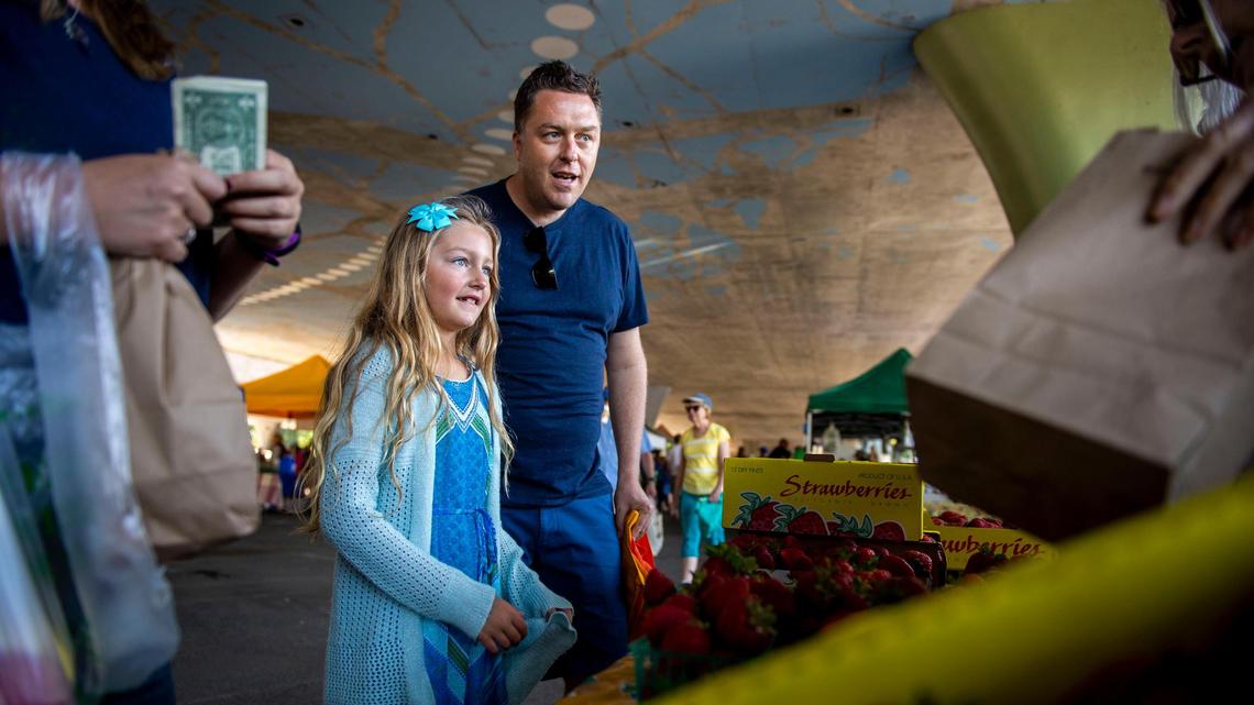 Oliver Ridgeway and daughter Ella Ridgeway visit a local vendor to buy strawberries at the Certified Farmers’ Market on W and 8th streets on Sunday, June 2, 2019.