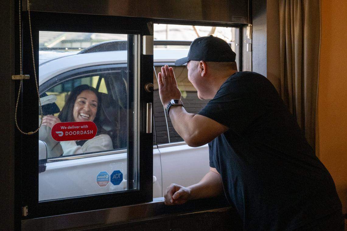 Owner Ulemj Tsogtgerel waves to a customer who just picked up her order of sushi at the take-out window on Monday in Arden Arcade. His restaurant is believed to be the only drive-thru sushi spot in the Sacramento region.